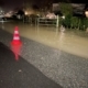 Zur Hälfte überschwemmte Dorfstraße in Höhe der Beek, abgesperrt mit Leuchtkegel